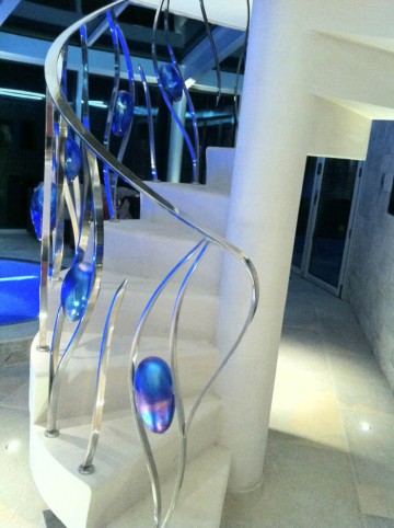 25. Spiral Moleanos stone staircase with chrome and blue glass balustrade